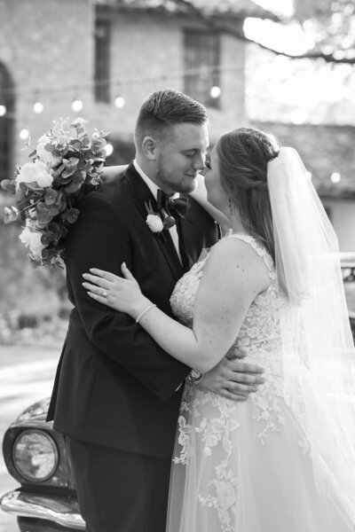 An Austin-based wedding photographer captures the unforgettable moment when a bride and groom share a tender kiss in front of a classic car.