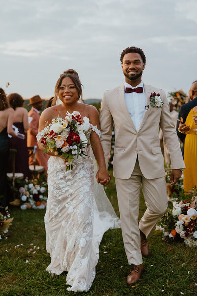 smiling couple walks down aisle