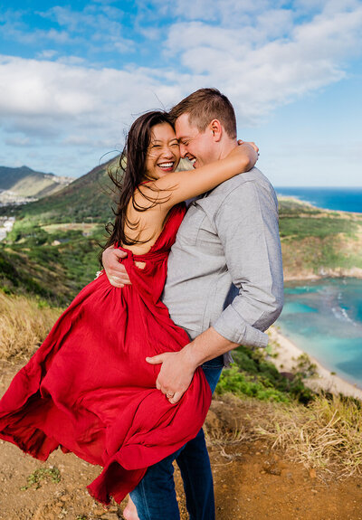 man lifting woman up for embrace cliffside engagement