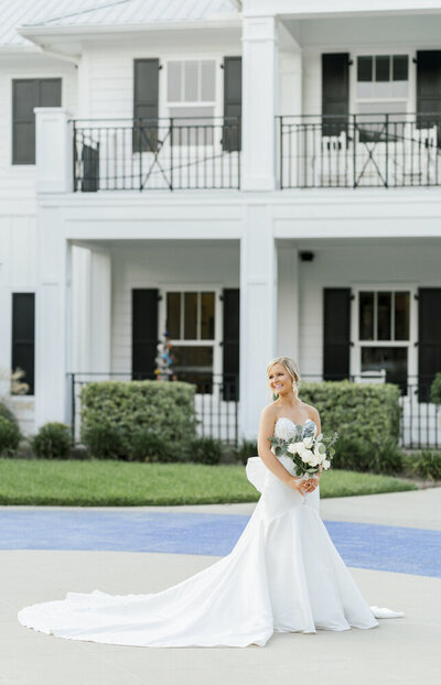 bride smiling and holding bouquet in front of Coastal Arts Center