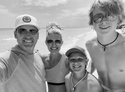 Lon Stroschein with his family at the beach, smiling in sunglasses and swimwear
