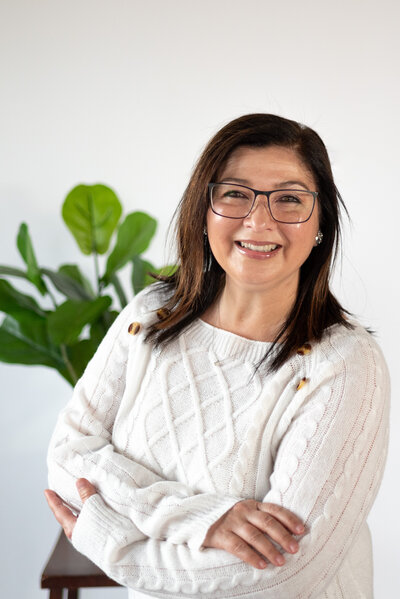 Elegant studio headshot portrait of a woman with a green plant in the background on a white backdrop. Perfect for professional profiles, this photo captures a polished and approachable look, ideal for business or personal branding in Salem, Oregon.