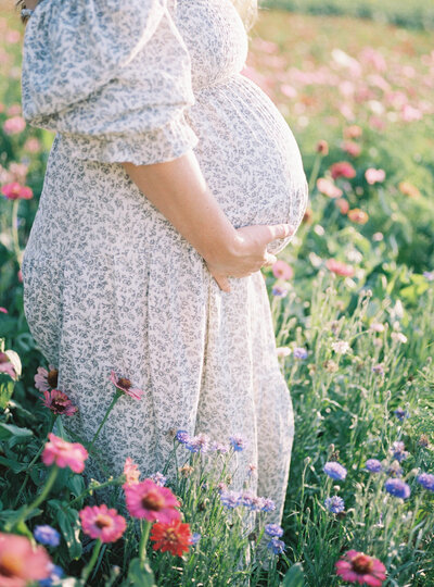 Close up of pregnant belly in Nothing Fits But dress in a field of flowers by Richmond Maternity Photographer Adrianne Shelton