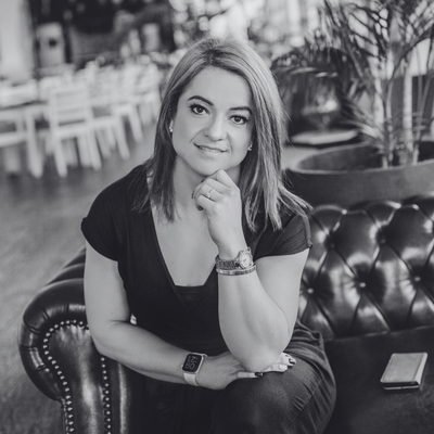 Jessica wearing a white blazer, smiling as she writes in her planner