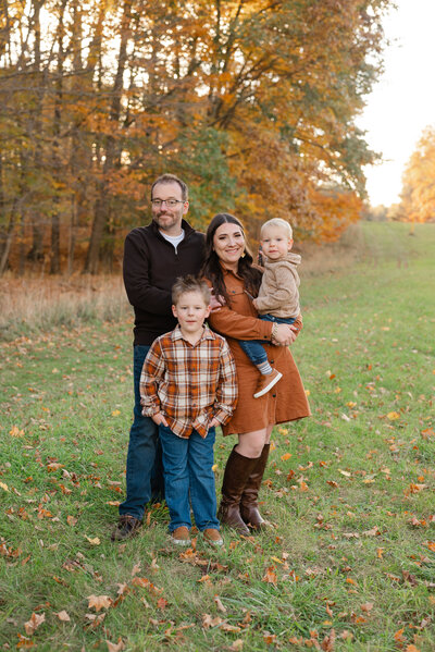 Family of four posing outdoors among vibrant autumn foliage