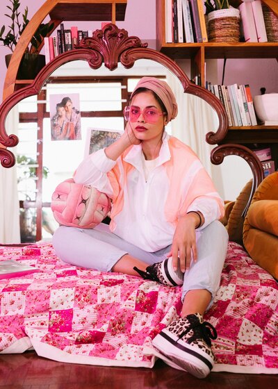 Girl with pink glasses sits in a pink room