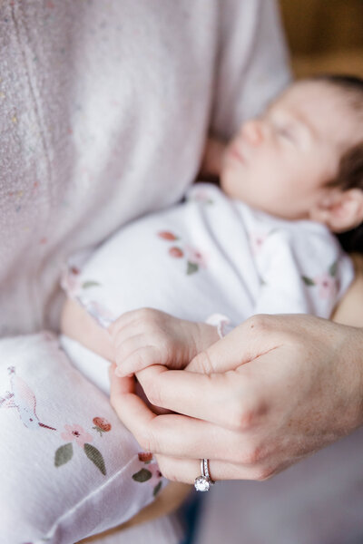 close up photo of mom holding baby girls finger