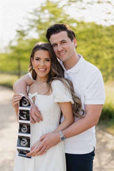 Couple embracing each other on beach with hands on baby bump