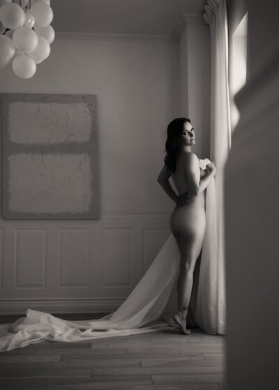 Moody black-and-white boudoir portrait featuring dramatic lighting and shadows