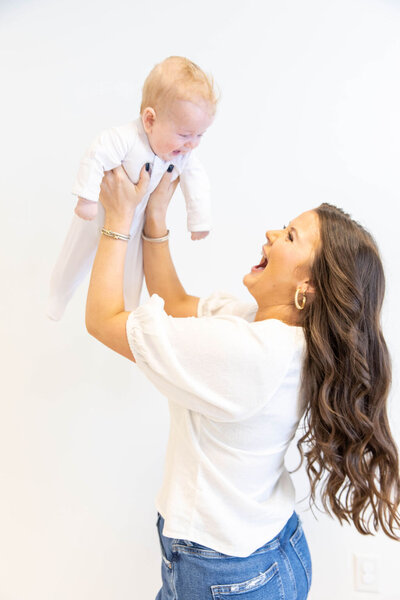 Woman playfully holding her baby up in the air