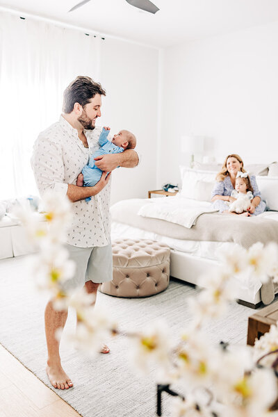 Bright photo of dad holding new baby boy with mom and little sister smiling near st pete