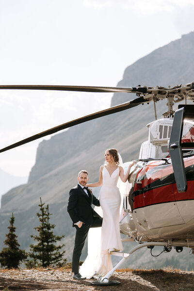 photo of couple kissingin front of helicopter that was part of their Banff elopement package
