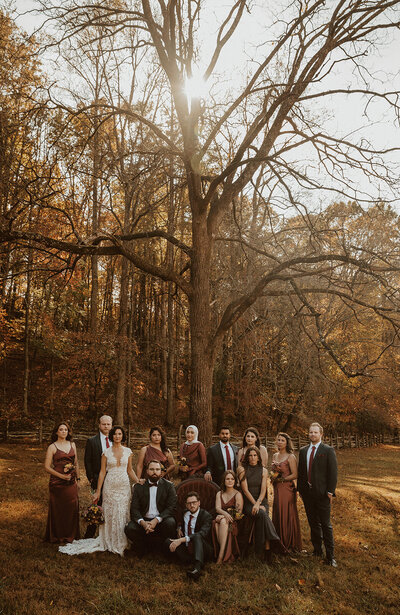wedding party poses on vintage red couch in front of tree