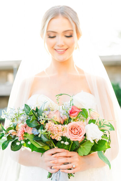 Bride with veil holding big rose bouquet with pink flowers
