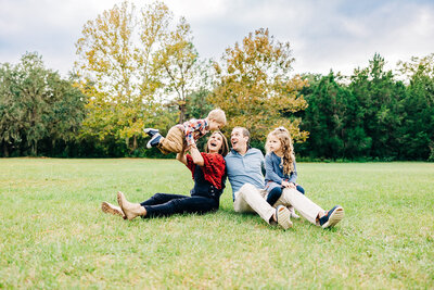 Candid photo of a family of four playing in an open field during a photographer session