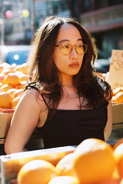 Asian woman smiling with curly hair and light green crop halter top and blue jeans