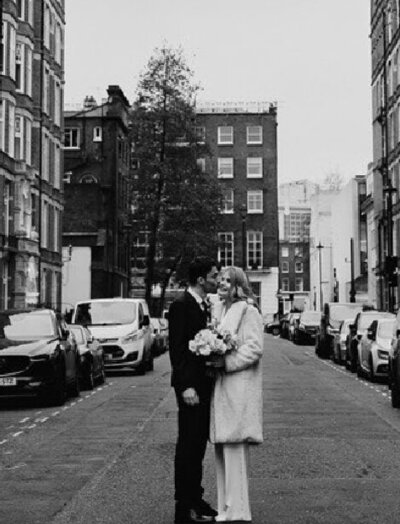 groom kissing brides cheek in street