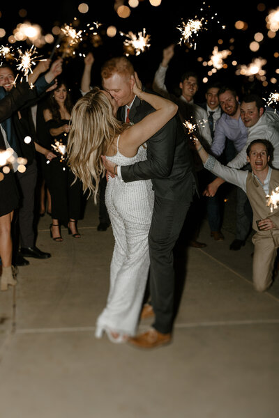 bride and groom kissing with a sparkler send off