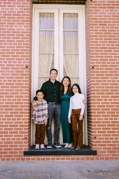 Family of four stand in a doorway between brick