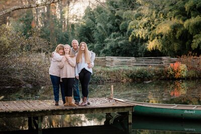 Beautiful family portrait on a dock with a canoe at Turnipseed Nursery in Fayetteville Georgia