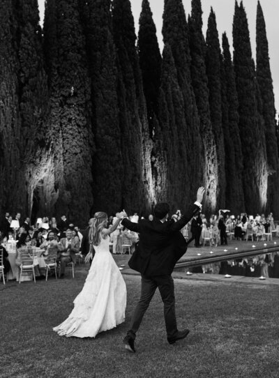 bride and groom arms raised walking