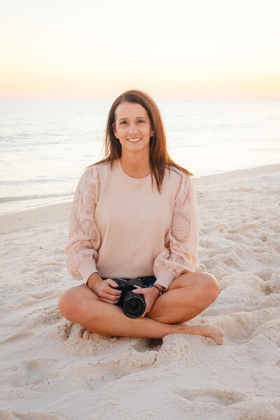 Photographer Michelle Law sitting on beach during sunset with camera