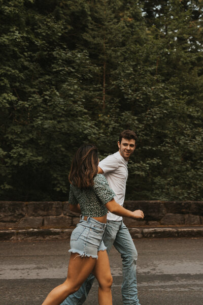 Couple running down a road laughing in Glacier National Park