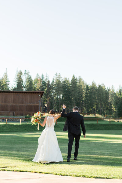 bride and groom walking away and raising their hands in the air to celebrate