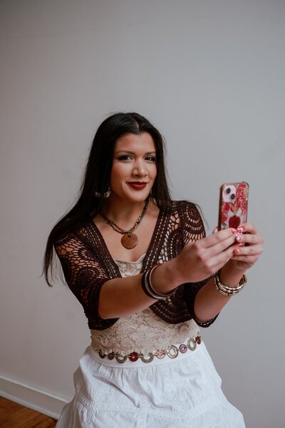 Jade holding a phone and smiling for the camera