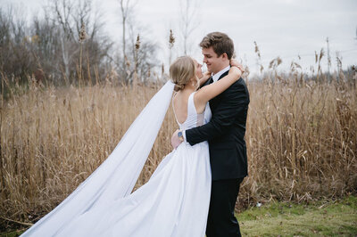 bride and groom hugging in open field at The Palazzo Grande, a wedding venue in Michigan