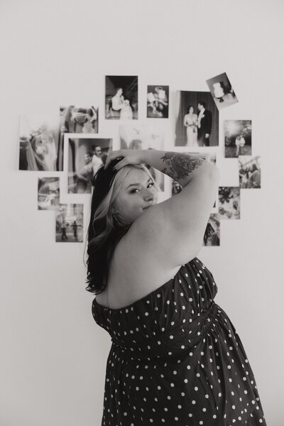 Photographer brand photo posing in front of wall of photos