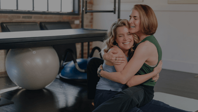 two pilates lead instructors hugging 