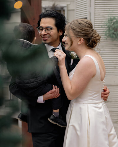 A bride and groom dance with their small son, smiling at him during their Catholic wedding reception in Oak ridge, Tennessee