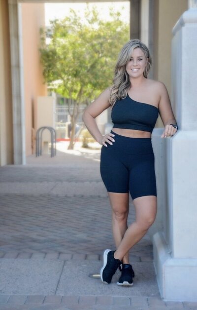 Britni leaning on wall smiling in black