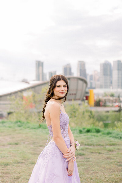 Brunette girl in lilac graduation dress overlooking the Saddledome, in Calgary AB