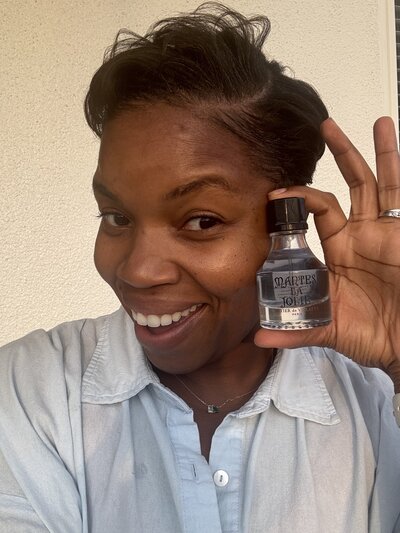 Career coach for working women holding Mantes La Jolie perfume bottle outside