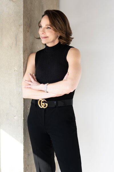 Rebecca leaning her shoulder against a wall smiling