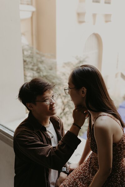 couple kissing and holding hands in front of building