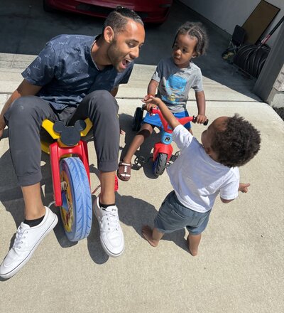 Man sitting on a tricycle playing with kids