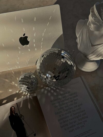 Disco balls reflecting light beside a laptop and statue – Brand Identity Elevation