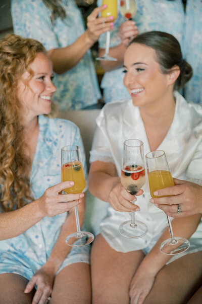Bristol Train Station Wedding | bride and bridesmaid clink glasses full of mimosas in bridal suite