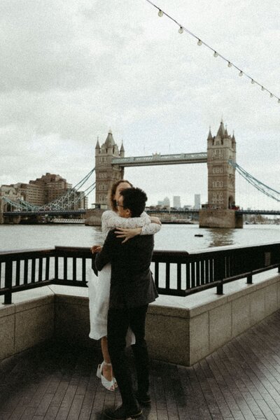 A couple embraces in front of Tower Bridge during a London elopement wedding.