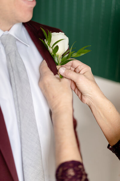 groom with boutonniere being fixed on suit