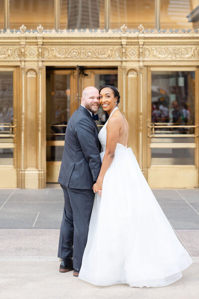 Downtown Chicago engagement photos along the Gold Coast; a man in a blue shirt and woman in a blue floral dress in front of a stately building