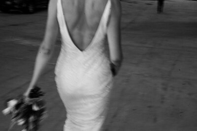 black and white of a bride walking away holding bouquet