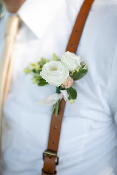 Detail photo of a boutonniere on a groom's suspenders