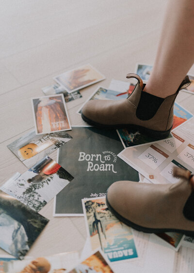 Brown boots standing on top of a pile of papers and photos on the floor