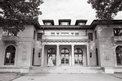 a bride standing on the front steps of a mansion