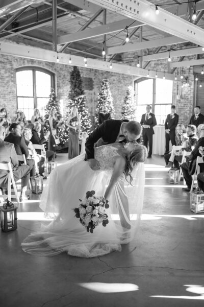 Couple kissing during ceremony dip in front of guests