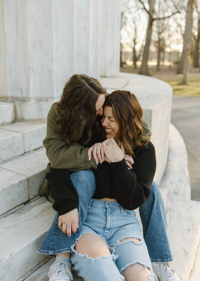 Queer lesbian couple cuddle on the steps of the d.c. war memorial in washington d.c.